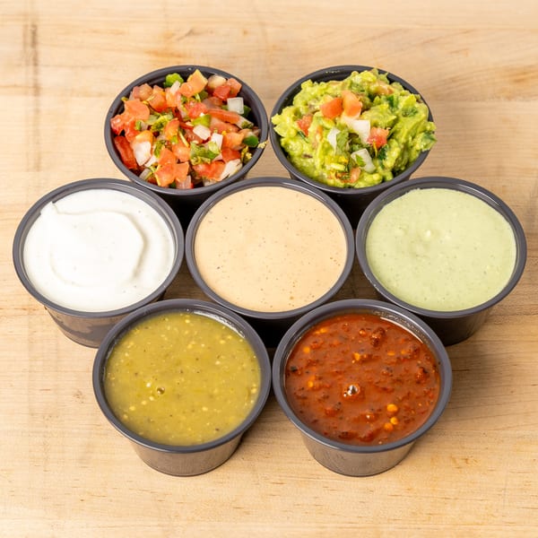 Seven small cups of various sauces and salsas, including guacamole, pico de gallo, and creamy dips.