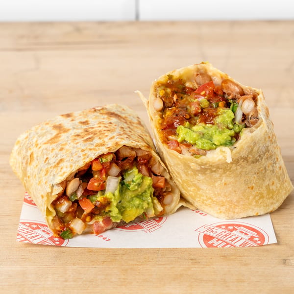 Two halves of a burrito filled with guacamole, salsa, and beans, on a branded paper.